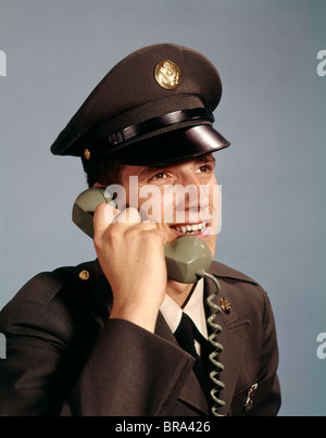 1960ER JAHRE LÄCHELNDE JUNGE MANN SOLDAT IN ARMY UNIFORM RETRO AM TELEFON SPRECHEN Stockfoto