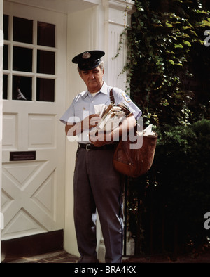 MITTE DER 1970ER-JAHRE IM ALTER VON MAILMAN WEIßE TÜR SORTIEREN DER POST ZUR AUSLIEFERUNG BEREIT Stockfoto