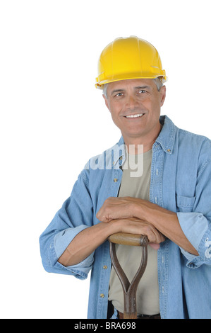 Workman, stützte sich auf den Griff seine Schaufel. Mann trägt einen Schutzhelm und lächelt in die Kamera. Stockfoto