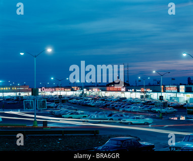 1960ER JAHRE NACHT LICHTER DER PARKPLATZ IM FREIEN IN EINEM EINZELHANDEL SHOPPING CENTER STRIP MALL NEW JERSEY USA Stockfoto