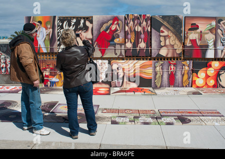 Künstler Malerei mit einem potenziellen Kunden bei der St Kilda Esplanade Sonntagsmarkt anzeigen Stockfoto