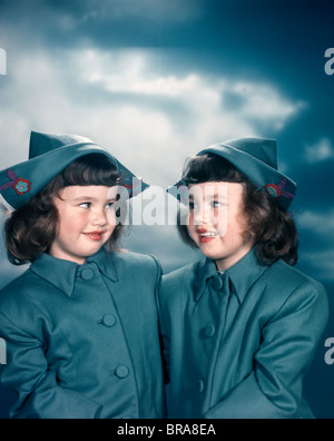 1940S 1950S WIES PORTRAIT ZWILLINGSMÄDCHEN TRAGEN BLAUE NIEDERLÄNDISCHEN OUTFITS MÄNTEL TRADITIONELLEN HÜTE Stockfoto