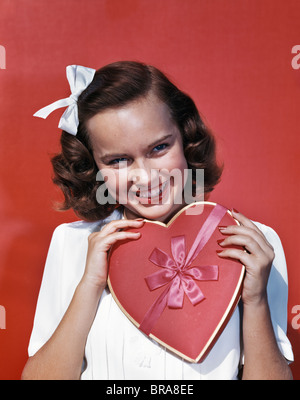 1940S 1950S GEFORMTE LÄCHELNDE JUNGE FRAU HÄLT ROTES HERZ VALENTINE CANDY BOX Stockfoto