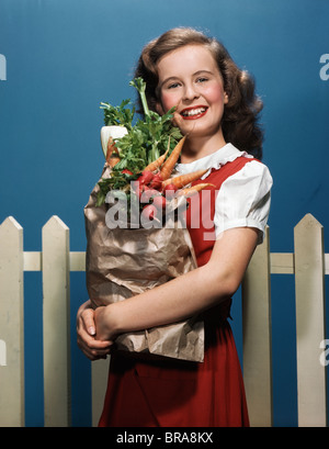 1940S 1950S LÄCHELN AUF DEN LIPPEN TEENAGER-MÄDCHEN TRAGEN BEUTEL MIT LEBENSMITTELN UND GEMÜSE Stockfoto