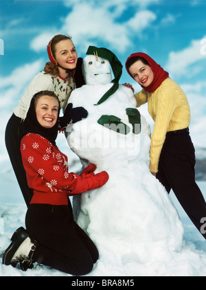 1940S 1950S STELLTE DREI FRAUEN UM EINEN SCHNEEMANN Stockfoto