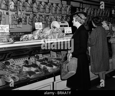 1940ER JAHRE FRAUEN IN DER METZGEREI IN VITRINE VON FLEISCH Stockfoto