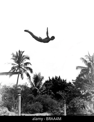 1940ER JAHRE MANN BALANCIERT, MIDAIR ARME SPRINGEN VOM SPRUNGBRETT IN POOL Stockfoto