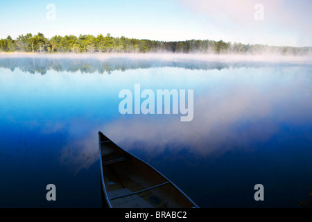 Ein Kanu in den nebligen Sonnenaufgang auf See Dennison, Massachusetts, USA. Stockfoto