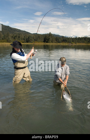 Fischer fangen eine Silberlachs (Coho) (Oncorhynchus Kisutch) mit jungen netting-Fisch, Coghill Lake, Alaska, USA Stockfoto