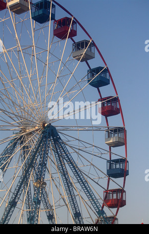 Riesenrad mit roten, weißen und blauen Autos vor einem blauen Himmel. Stockfoto