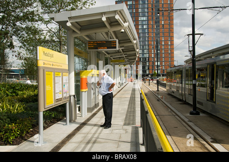 Mann liest ein Schild an der Metrolink-Straßenbahn-Haltestelle am MediaCityUK, Salford Quays, Manchester, England, UK Stockfoto