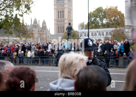 Ein Metropolitan Police Officer steht vor der Masse hinter den Barrieren um Parliament Square während Armistice Day Parade. Stockfoto