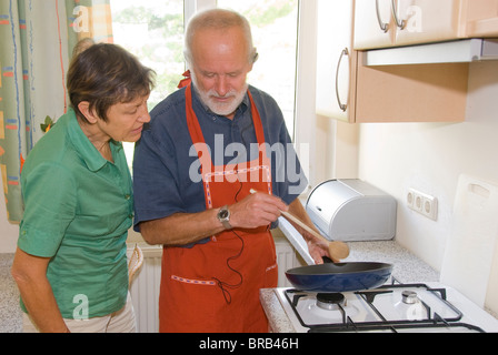 Ältere Mann kochen, Frau über die Schulter schauen Stockfoto