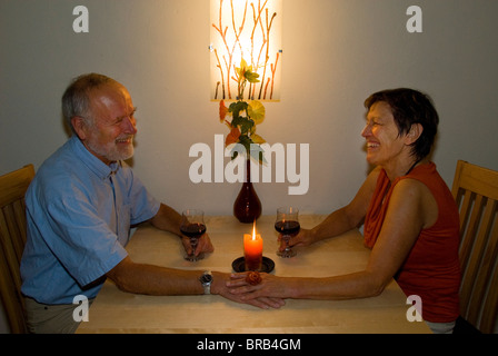 Älteres Ehepaar mit einem Glas Wein bei Kerzenschein Stockfoto