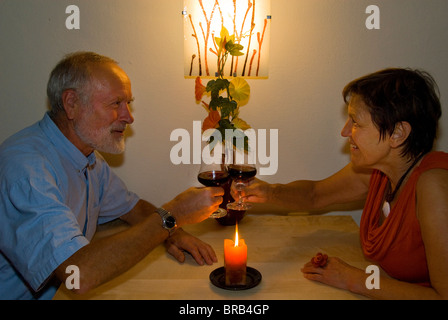 Älteres Ehepaar mit einem Glas Wein bei Kerzenschein Stockfoto