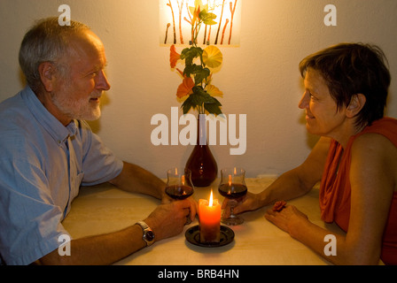 Älteres Ehepaar mit einem Glas Wein bei Kerzenschein Stockfoto