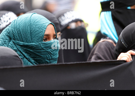 Eine junge Muslimin in ein Kopftuch schaut auf einen nahe gelegenen EDL-Protest, LONDON, UK Stockfoto