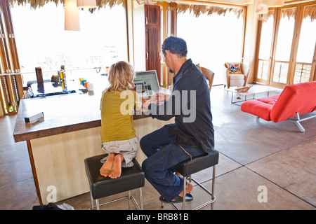 Mann arbeitet auf Laptop neben Kind Stockfoto