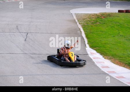 Mann ein Go-Kart fahren und heben den arm Stockfoto