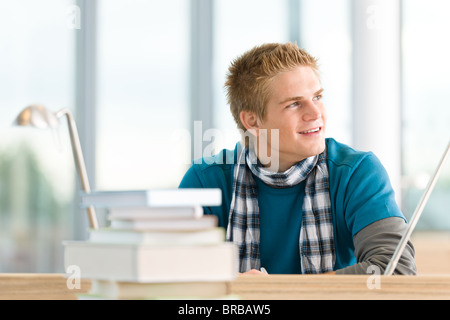 Männliche Schüler mit Büchern sitzen am Tisch an der High school Stockfoto
