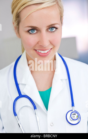 Ein attraktives Lächeln Ärztin trägt einen weißen Kittel und Stethoskop in einem Krankenhaus. Stockfoto