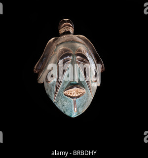Geschnitzte afrikanische Stammes-Holzmaske, schießen aus der Front, dunklem Holz mit bemaltem Gesicht, Tier am Kopf zeigen Zähne. Afrika, Stockfoto