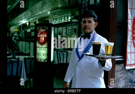 Ein Kellner vor Rio De Janeiro berühmt Bar Luiz mit einem Tablett mit Bier vom Fass - Lager und Stout. Stockfoto