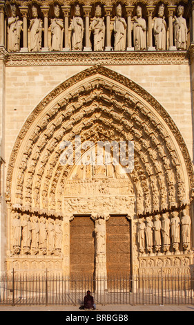 Frau beten vor dem jüngsten Gericht Tor, Westfassade, Kathedrale Notre-Dame, UNESCO-Weltkulturerbe, Paris, Frankreich Stockfoto