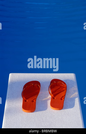 Gelb und Orange Flip Flops auf dem Sprungbrett eines Schwimmbades Stockfoto