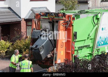 Bin Männer Entleerung Hausmüll aus wheelie Bins in Müllwagen auf der Straße. Anglesey Wales, UK, Großbritannien. Stockfoto