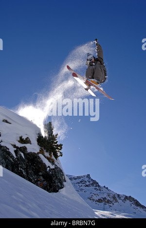 Skifahrer, die von einem Felsen in St. Moritz in der Schweiz während Spinnen und packte ihre Ski springt Stockfoto