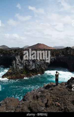 dh Coast LOS HERVIDEROS LANZAROTE Touristen fotografieren Wellen brechen Lava Meer Bögen und Meereshöhlen Höhlenbogen Stockfoto