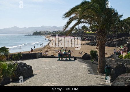 dh Strand PUERTO DEL CARMEN LANZAROTE Touristen sitzen auf Promenade Bank mit Blick auf Strand Stockfoto