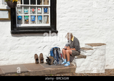 Eine Frau Wanderer schreiben Postkarten auf der alten Befestigungsblock vor der Sonne Gasthaus im Dorf Dent, Dentdale, Cumbria Stockfoto