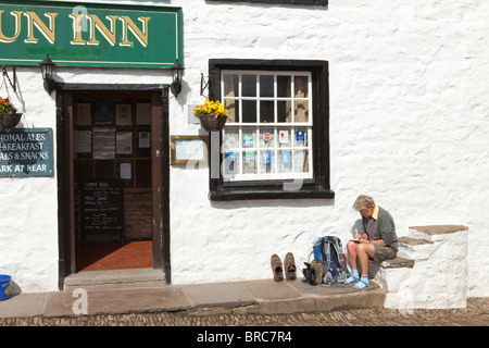 Eine Frau Wanderer schreiben Postkarten auf der alten Befestigungsblock vor der Sonne Gasthaus im Dorf Dent, Dentdale, Cumbria Stockfoto