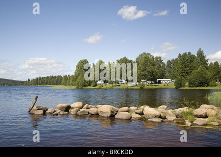 Lake Ovre Brocken in der Nähe von Torsby mit Damm aus Steinen und Campingplatz im Hintergrund, Värmland, Schweden Stockfoto