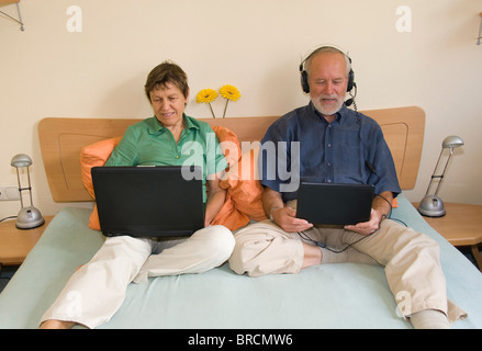 Älteres Paar mit Laptop und Netbook auf Bett Stockfoto