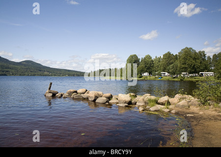 Lake Ovre Brocken in der Nähe von Torsby mit Damm aus Steinen und Campingplatz im Hintergrund, Värmland, Schweden Stockfoto