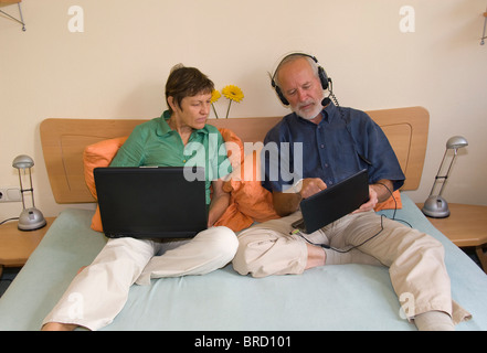 Älteres Paar mit Laptop und Netbook auf Bett Stockfoto