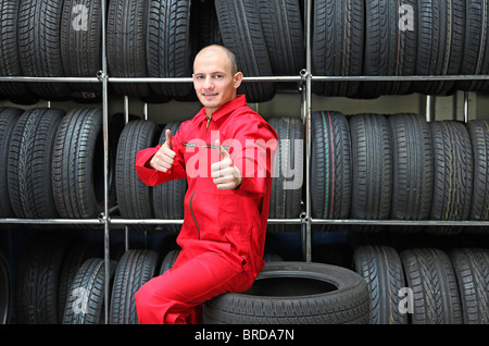 Ein motivierter Arbeiter in einem Reifen-Workshop eine positive Geste. Stockfoto