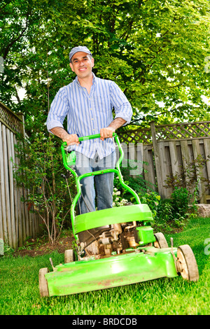 Mann mit Rasenmäher in begrünten Hinterhof Stockfoto