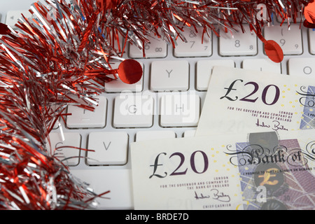 Haufen von zwanzig Pfund Sterling Banknoten auf einer Computertastatur mit Lametta Weihnachtsdekoration Stockfoto