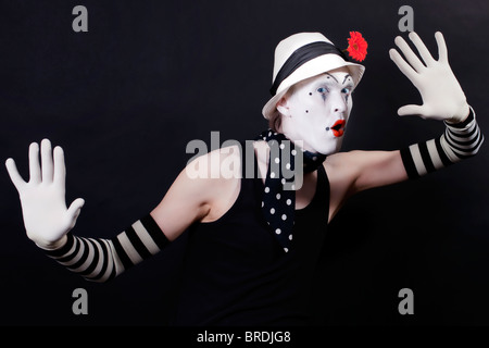 Lustige Mime in weißen Hut mit roter Blume auf einem schwarzen Hintergrund Stockfoto