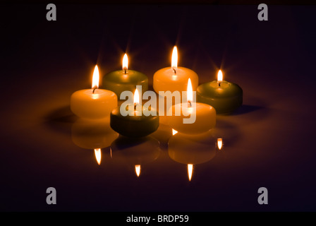 Sechs Kerzen auf einem dunklen reflektierenden Boden. Stockfoto