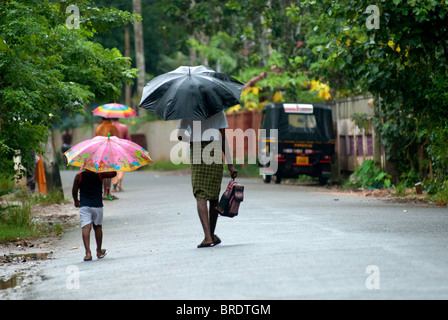 Ein Alter Mann ist auf dem Weg zu seinem Enkel zur Schule während eines Monsuns fallen; Regentag in Alappuzha; Alleppey, Kuttanad, Kerala. Stockfoto