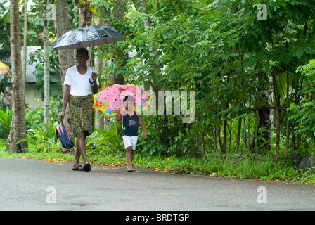 Ein Alter Mann ist auf dem Weg zu seinem Enkel zur Schule während eines Monsuns fallen; Regentag in Alappuzha; Alleppey, Kuttanad, Kerala. Stockfoto