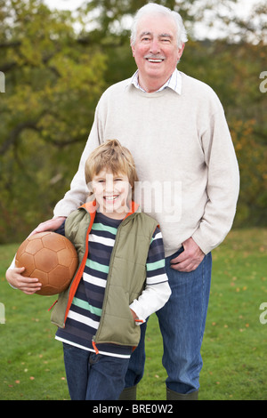 Großvater mit Enkel halten Fußball außerhalb Stockfoto