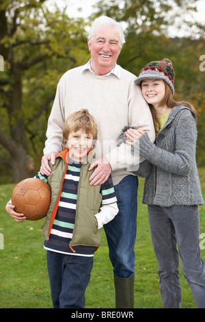 Großvater mit Enkel halten Fußball außerhalb Stockfoto