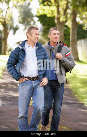 Zwei männliche Freunde, die zusammen im Freien im Herbst Park spazieren Stockfoto