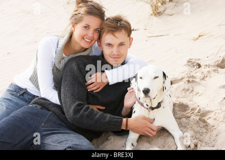 Porträt des romantischen Teenager-Paar am Strand mit Hund Stockfoto